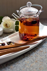 Hot aromatic fruit tea in a glass teapot. Traditional tools for tea drinking and Chinese tea on a light background. The concept of tea drinking. Lifestyle wabi sabi.