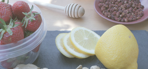 lemon, strawberry, ginger, strawberry honey and tea on a dignified and wooden background