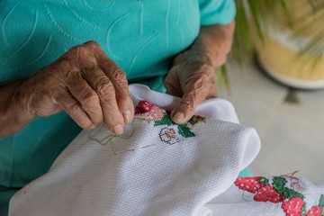 Mãos de idosa fazendo bordado