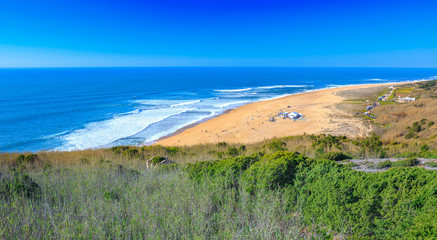 Awesome aerial sunny seascape coastline of Atlantic ocean. View North Beach (Praia do Norte). Most famous place of giant breaking waves for surfers from around the world. Nazare, Portugal.