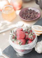 lemon, strawberry, ginger, strawberry honey, apple and tea on a dignity and a wooden background