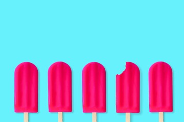 Group of bold pink popsciles on a pastel blue background. One with bite removed.