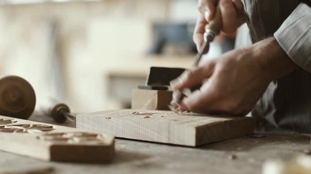 Professional carpenter carving wood using a gouge