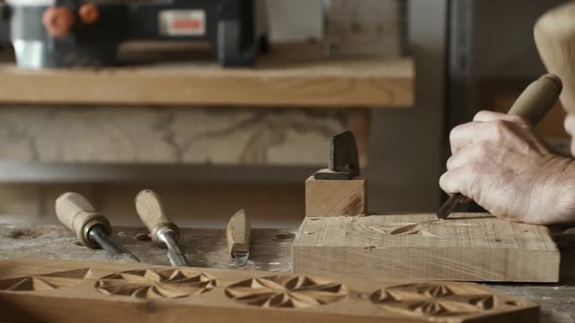 Skilled carpenter carving wood with hammer and chisel