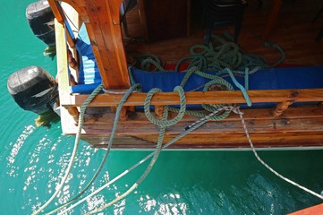 Part of a wooden yacht and rigging ropes.