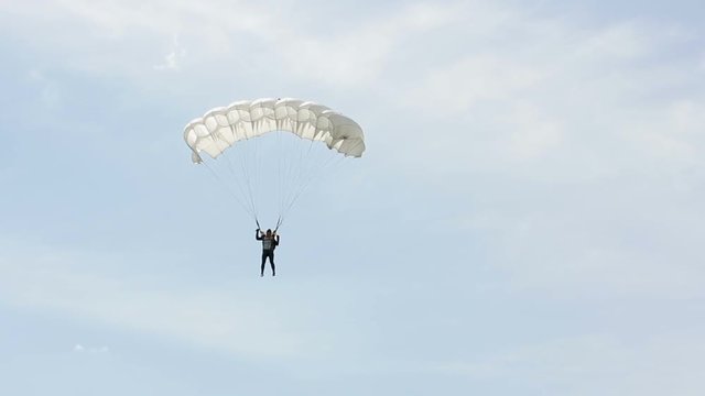 Man extremely descends with a parachute to the ground. Parachute flight. The view from the ground
