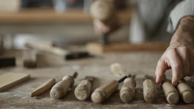 Skilled carpenter carving wood with mallet and chisel