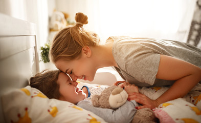 mother wakes her daughter in bed in  morning