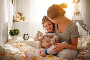 mother wakes her daughter in bed in  morning