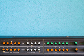 Old synthesizer with colorfull switches on blue background