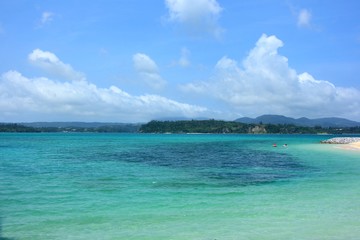 沖縄の青い空と白い雲とエメラルドグリーンのビーチ