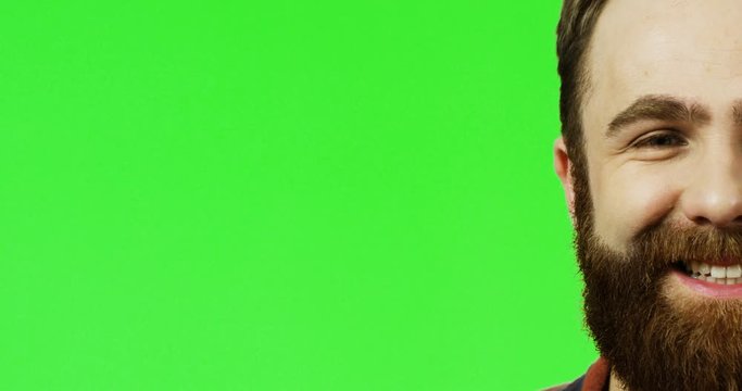 Portrait of the half face of the Caucasian man with a red beard smiling on the chroma key background. Green screen.