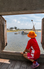 A young school girl sit in front of a window looking at work on art & decorations in the wetlands....