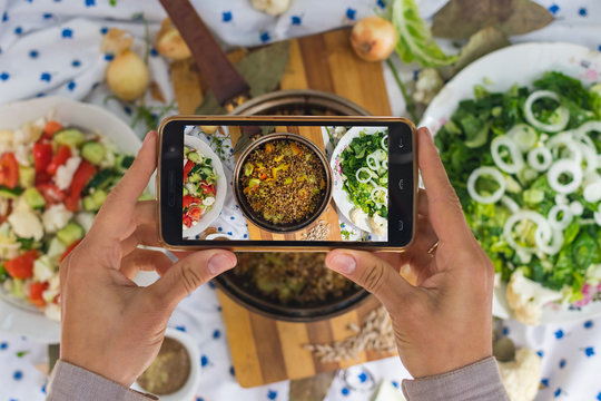 Smartphone photography of food. Woman hands take phone photography of lunch or dinner. Russian traditional buckwheat porridge cooked in pot. Good for social media publications or blogging.