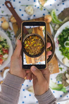 Smartphone photography of food. Woman hands take phone photography of lunch or dinner. Russian traditional buckwheat porridge cooked in pot. Good for social media publications or blogging.