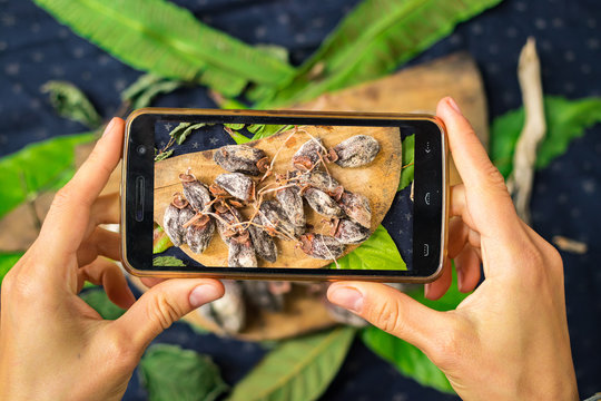 Smartphone photography of food. Woman hands take phone photography of sweet dried persimmons. Arabian asian dessert. Good for social media publications or blogging.