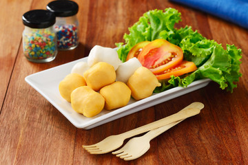 Fish balls with vegetables on dish, wooden spoon fork on wooden table.
