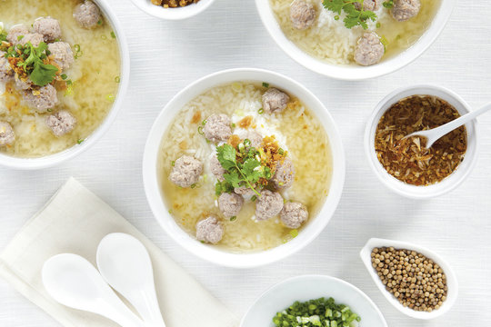 Rice porridge with pork chops and seasoning in white bowls on top view white table, Chinese food.
