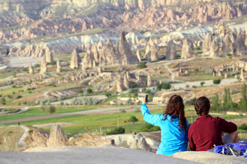 Fototapeta na wymiar guy and a girl doing a selfie with hills of volcanic rock in the Cappadocia valley, Turkey