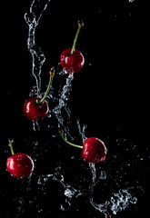 Fototapeta na wymiar cherries in the spray of water, fresh fruits falling in water