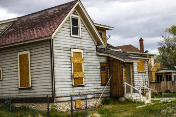 Fototapeta na wymiar Abandoned Home In Disrepair With Boarded Up Windows