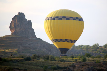 yellow balloon with people flying near the rock