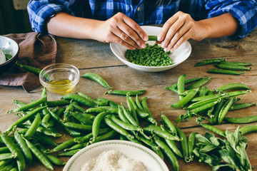 Healthy food concept Woman cooking vegetarian risotto green peas mint goat cheese Raw ingredients cooking risotto wooden table Rustic style