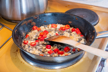Wooden flipper frying chili with garlic on vegetable oil