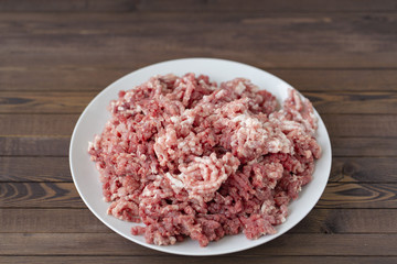 fresh raw minced beef in a plate close up on a rustic wooden table
