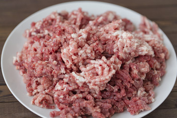 fresh raw minced beef in a plate close up on a rustic wooden table