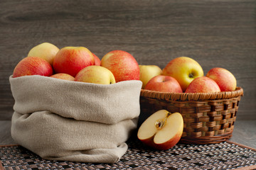 Harvest of apples in a bag. A lot of red apples in a bag and a wicker basket. A lot of fruit on a wooden background.