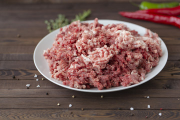 fresh raw minced beef in a plate close up on a rustic wooden table