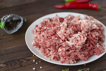 fresh raw minced beef in a plate close up on a rustic wooden table
