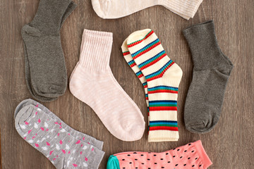 Many socks on a wooden background. Socks of different colors for the cold seasons. View from above. Clothes on a gray background.