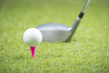 Golf balls and golf club on green grass