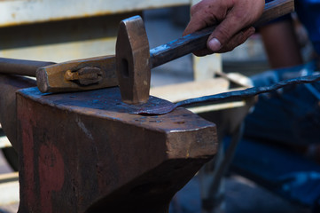 blacksmith performs the forging of hot glowing metal on the anvil