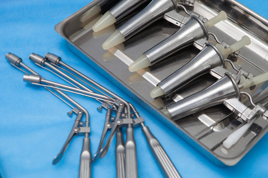 Anoscopes and ligators for the diagnosis and treatment of hemorrhoids made of stainless steel on a blue medical tablecloth