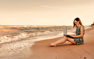young woman using laptop on the beach