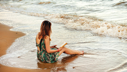 Girl reading a book at the beach