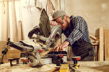 experienced  carpenter using circular saw for cutting wooden boards. Construction details of male...