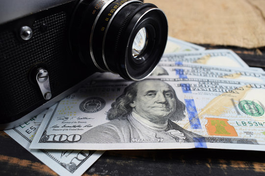 earnings in photography, a camera and money (dollars) are on the table