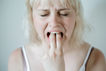 Portrait of young blond woman, annoyed, frustrated fed up sticking her finger in her throat. Mental disorders bulimia, addiction. - obrazy, fototapety, plakaty