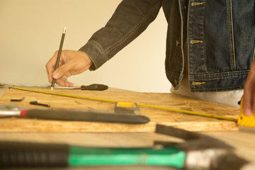  Close-up of male carpenter holding a measure tape in workshop .