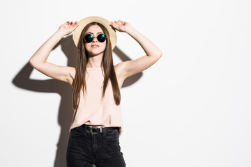Beautiful young woman in fashion hat and sunglasses posing on white background