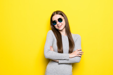 Fototapeta premium Young fashion girl with sunglasses in dress with crossed hands on yellow background