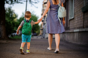 Back view of mother going with a little son with a backpack © fesenko