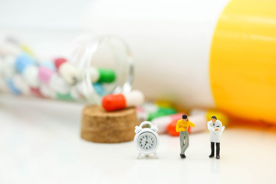 Miniature people : Doctor and patient with Capsule pill and  alarm clock for warning about eating medicine time,Drug resistance concept
