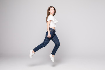 Full length portrait of a cheerful happy woman jumping and looking away isolated over white background