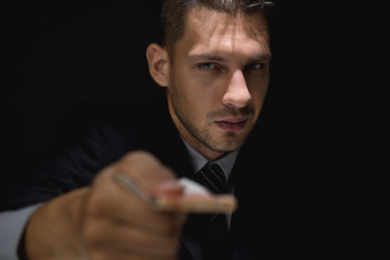 Sly businessman giving bribe money in dark shadow