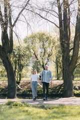 Fototapeta premium Beautiful young couple in the Park on a Sunny day, loving and happy. Walk and laugh with the dog. Pre-wedding shooting in nature. Casual style in clothing and European in processing